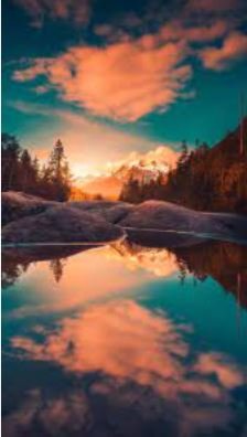 A serene sunset with vibrant clouds mirrored in calm water, creating a picturesque and tranquil scene