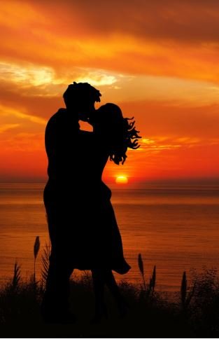 Silhouette of a couple sharing a kiss against a vibrant sunset backdrop, capturing a moment of love and intimacy.