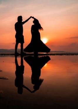 Silhouetted against a stunning sunset, a couple stands together on the beach, capturing a moment of love and tranquility.