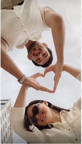 A couple creating a heart shape with their hands, representing affection and unity in their relationship.