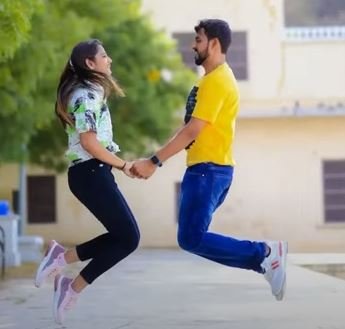 A joyful couple leaps into the air together, capturing a moment of happiness and shared excitement.