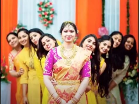 Several women dressed in bright yellow dresses stand together, smiling for a group photo.