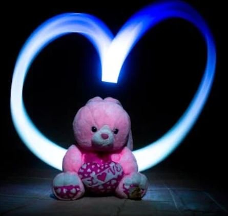 A teddy bear holding a heart-shaped light, radiating warmth and affection in a cozy setting.