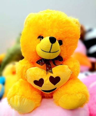 A cheerful yellow teddy bear featuring a heart on its chest, symbolizing love and warmth.