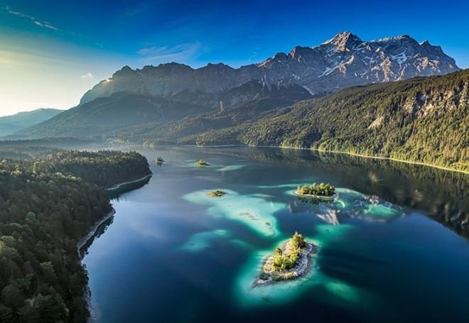 Breathtaking aerial image of a lake framed by the dramatic peaks of the Dolomites, illustrating the region's natural allure