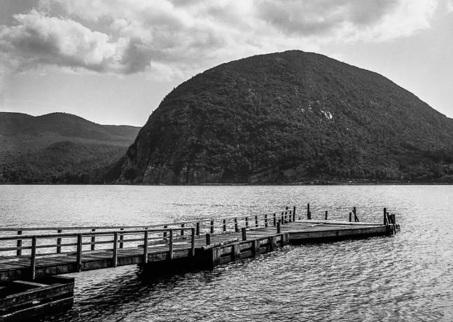 A black and white image showcasing a dock at the lake's edge, evoking a sense of peace and solitude.