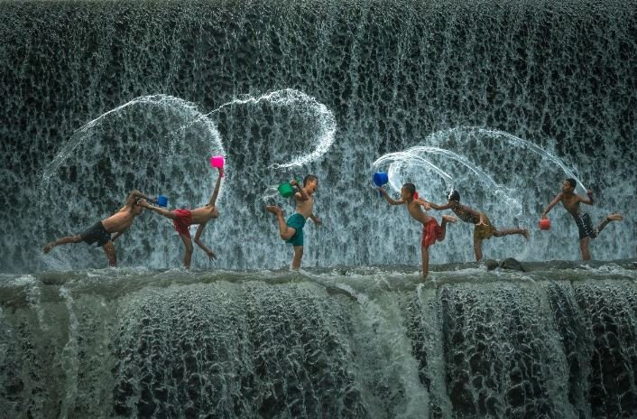 A lively group of people joyfully splashing in the water while engaging in a fun water balloon fight