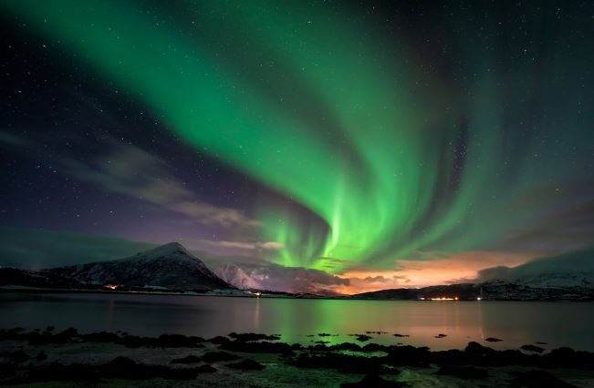 A stunning view of the aurora borealis illuminating the mountains in Norway, showcasing vibrant colors in the night sky.