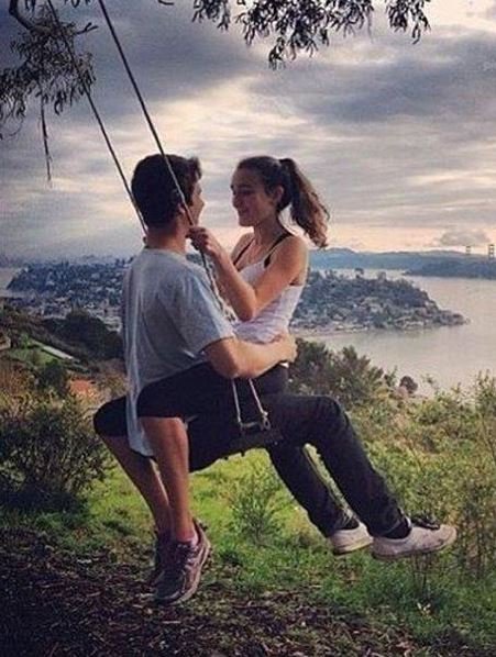 A man and woman enjoy a swing, overlooking a serene ocean view, capturing a moment of joy and tranquility together.