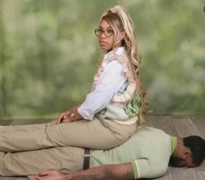 A woman sits on a man's back as he lies down, showcasing a playful and relaxed interaction between them.